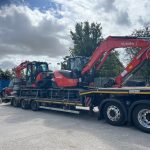 A photo of two red and black Kubota excavators being delivered to the Didcot Plant yard on the back of a very large trailer.