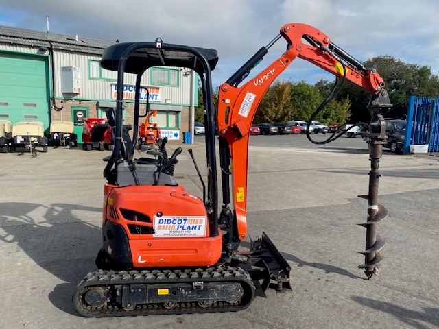 A photo of a bright orange and black mini excavator fitted with an earth auger in the Didcot Plant yard.
